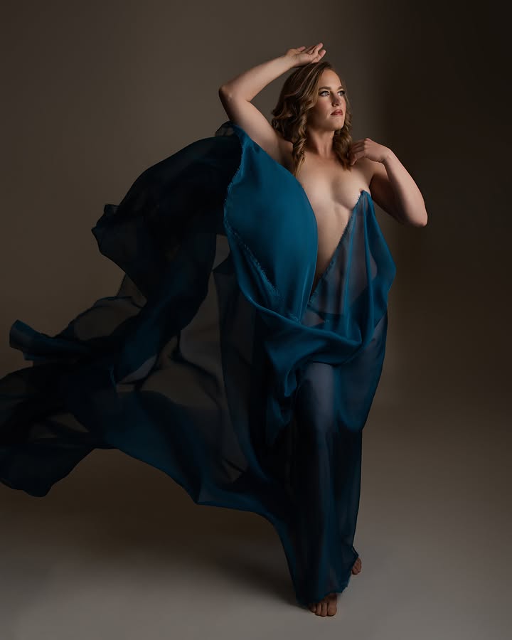 Woman in flowing deep blue fabric, dramatic studio portrait