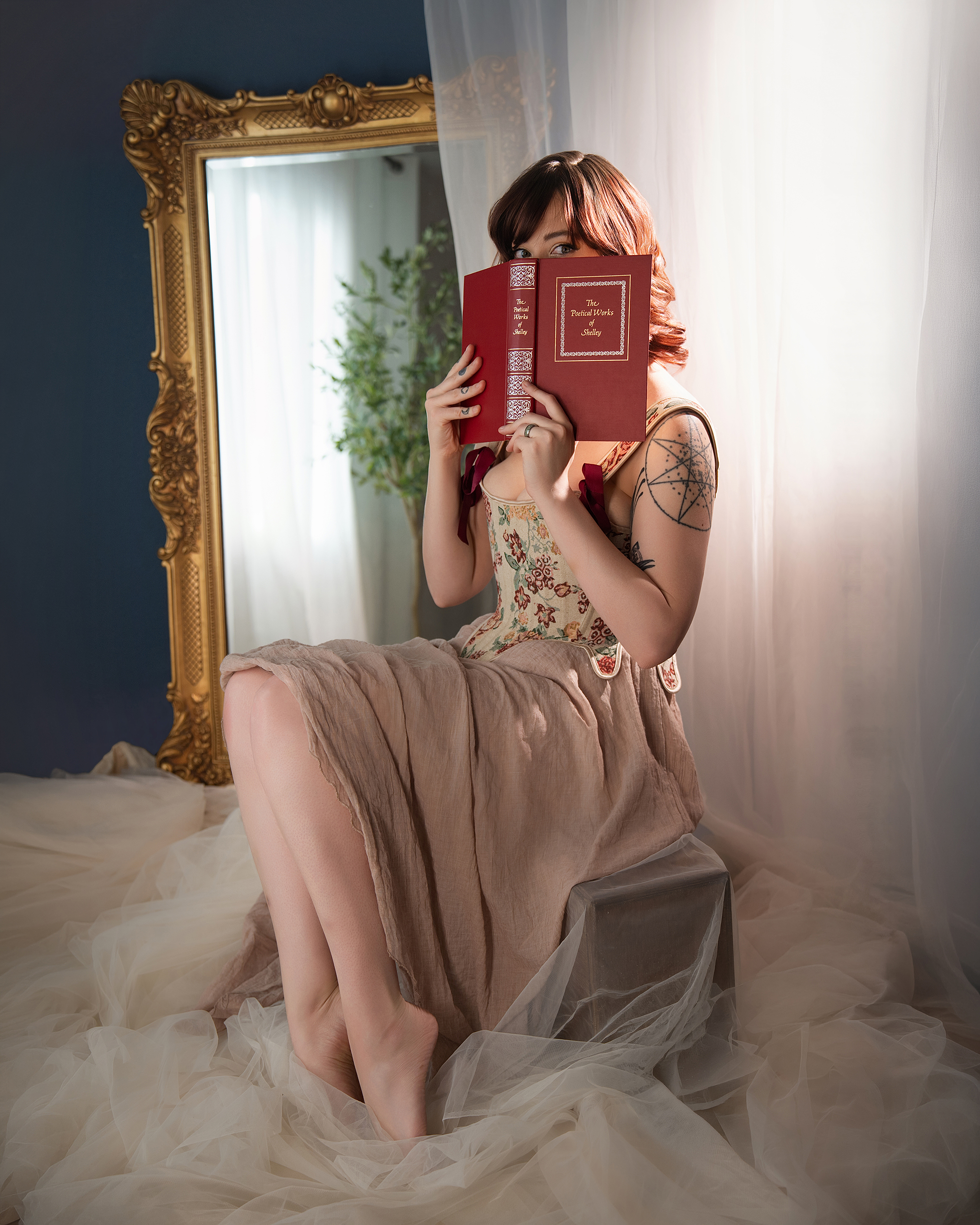 Soft gown, red book and gilded mirror, enchanted romantic boudoir mood